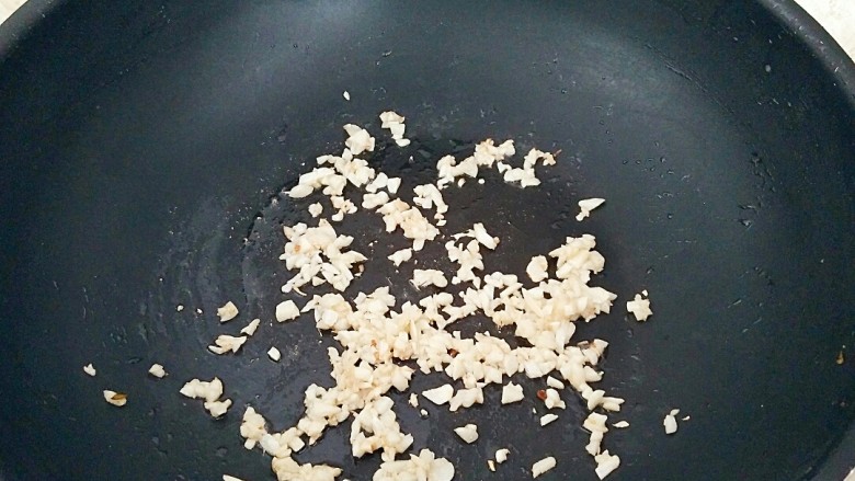 避风塘茄子,倒出多余的油,锅中留一点就可以,放入蒜粒小火煸炒出味。