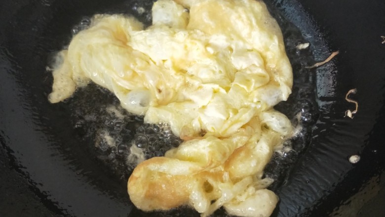 苦瓜青椒鸡蛋,锅内放入适量油,油温升起放入鸡蛋液,油炸至喧起,反面。