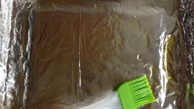 烤箱薯条,准备好烤盘,并在上面铺上锡纸。用小刷子均匀刷上一层油