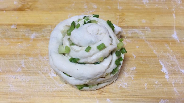 葱香煎饼,从一端向另一端卷起,压扁擀成薄饼