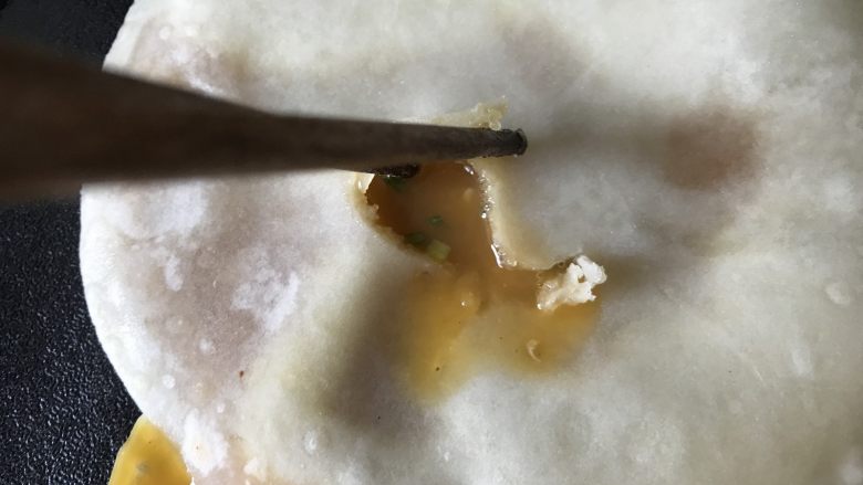 鸡蛋灌饼香肠卷,这时就可以用筷子开个洞,把鸡蛋液倒入饼中,再翻面,烙至两面金黄,蛋液变硬至熟即可出锅