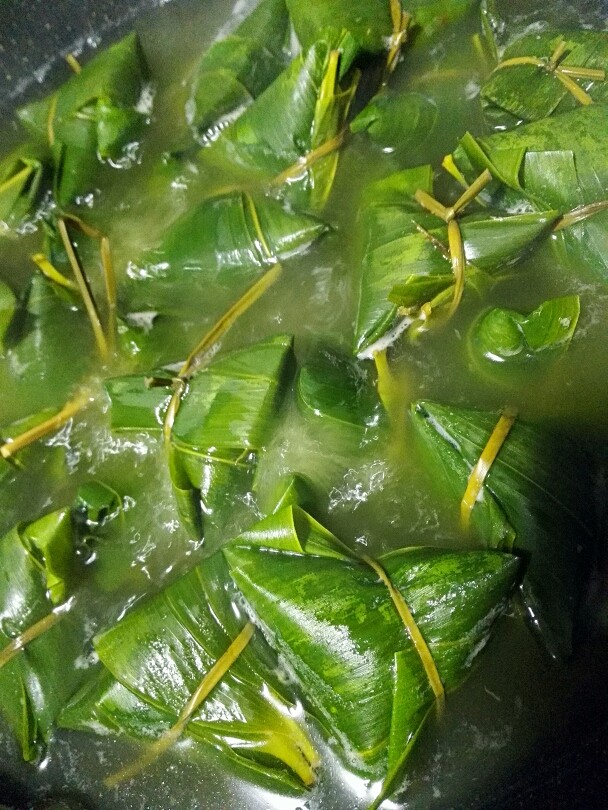 彩米花生香菇肉粽,大火煮开一会儿,转中火慢慢煮,用锅煮有一个好处,可以随时观察水量,煮一会也可以翻翻,煮的时间长短也要看粽子的量,我这里煮了一个半小时,然后关火。