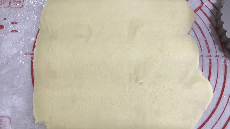 蜜桃乳酪派,第二天,取出派皮,台面撒少许手粉,用擀面杖先敲打派皮,再慢慢擀成圆形,厚度约4毫米