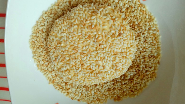 芝麻南瓜饼,包好的南瓜饼放入熟芝麻的容器里,沾满芝麻,依次做完。
