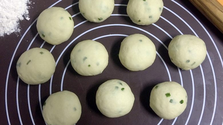 改良版墨西哥卷饼(香葱鸡蛋味),用刮板分割面团,称量每个小面团重量在50克左右,分割好的小面团全部揉圆
留两个面团在面板上,其余小面团放入揉面盆内,盖上布,以免表面风干
面板左上角舀一勺干面粉备用