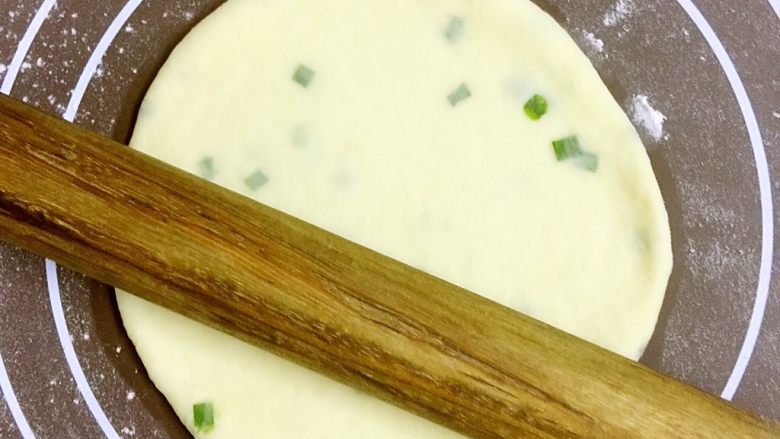 改良版墨西哥卷饼(香葱鸡蛋味),用擀面杖从面团中心向四周用力擀薄
每擀薄擀大一些,就揭开面饼,面板上再抹一层薄薄的面粉,继续擀薄。
因为面团比较湿软,一面擀薄时,另一面会粘在面板上不容易揭下来,一次性擀薄会造成揭开面饼时变形。