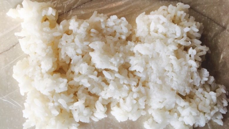 米饭卷,取保鲜袋一个,铺在桌上,保险带上,倒几滴油,用手抹开,这样防粘。用小勺舀<a style='color:red;display:inline-block;' href='/shicai/ 507'>米饭</a>,铺平。