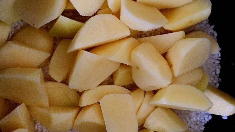 土豆鸡块焖饭,浸泡过的米去水,倒入电饭煲中,加少许水,刚刚没过大米的水量就可以了,先把土豆块挑出铺在大米上,这样土豆会更加入味。