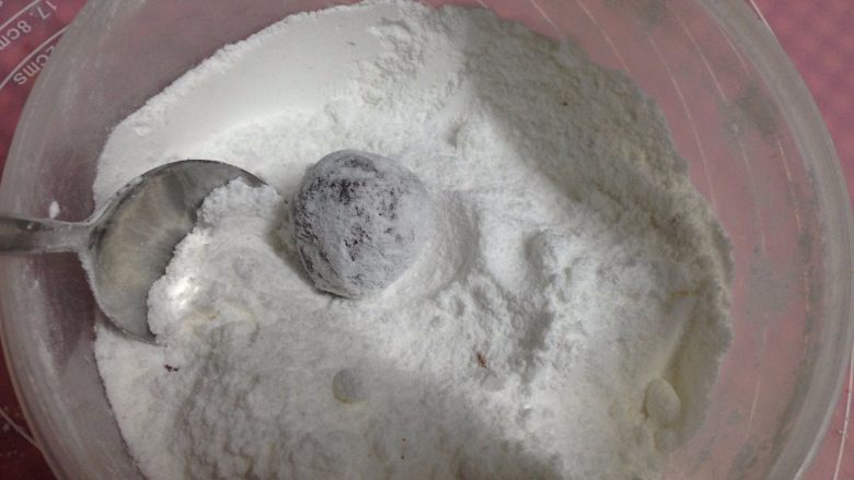 可可裂纹曲奇,放入装有糖粉的碗里,用勺子使其全部裹住糖粉,一定要沾均匀哟