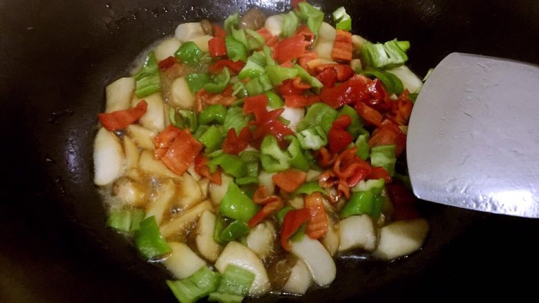 糖醋鸡腿菇（菌菇）,大火煮一两分钟，取青红椒碗，用铲子扒拉青红椒进锅内，因为碗底会有腌过的汁水，舍弃不用，会比较咸
将青红椒和鸡腿菇翻炒均匀，时间不超过半分钟