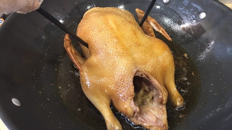 酱油焖鸭,油很烫,翻身时用小火,用筷子这样来配合鸭的翻身