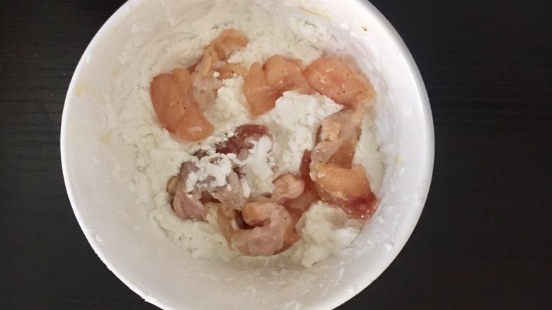 自制鸡米花,将腌制完成的鸡肉依次放入淀粉碗里,均匀地裹上一层淡粉。
