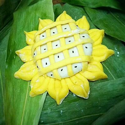 向日葵豆沙包,取适量面团切成条状。 横纵交错排在白色面团上, 点缀一下芝麻,做好的馒头生胚盖上蒸布饧发15分钟。冷水入笼,底下我垫的是粽叶,如果没用东西垫那蒸笼上事先须抹一层食用油防粘。