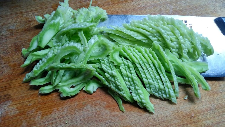 豆豉酸菜炒苦瓜,用刀将苦瓜斜着改切成片。苦瓜肉薄,这样切的话,片长成型一些。成菜装盘就会更美观。做菜讲心情,吃菜看卖像。刀功也不能马虎。
