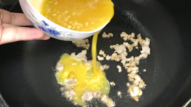 碎肉鸡蛋饼,把碎肉铺整齐后,就把混合好的蛋液均匀地倒入锅中,同时把火关小一些