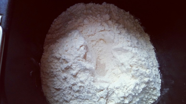 蔓越莓吐司面包,最后放入面粉,再面粉顶端挖个小洞,注意不要挖到液体。把酵母粉放入洞里,再用周边的面粉把酵母粉盖起来。