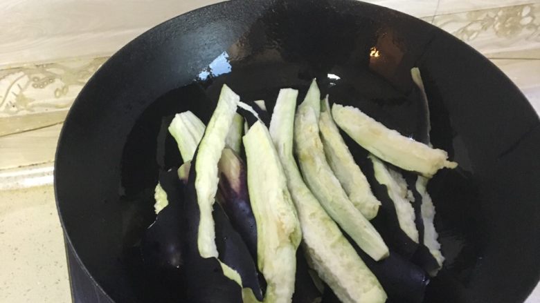 东北茄子酱,锅中放入适量的油,又热加入茄子条,土豆小块,葱,翻炒均匀
