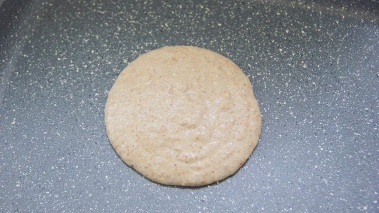 【燕麦香蕉Pancake】(素食低脂版),小火热锅,倒入一勺面糊,勺子保持不动让面糊自由倒入平底锅中,面糊会慢慢摊开成一个圆形。