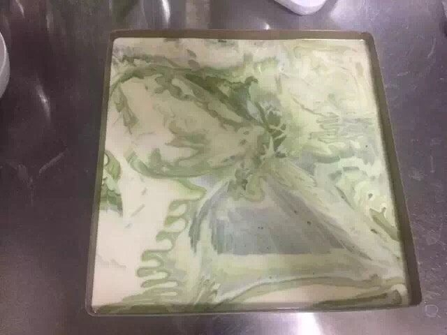抹茶大理石浮云卷,将糊倒入方盘中,用刮刀抹平,再震几下,震出气泡即可。