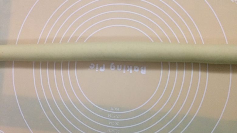刀切牛奶馒头,将面团按压成圆形,用擀面杖压成长方形面片,刷点水,卷成长龙,再搓均匀。