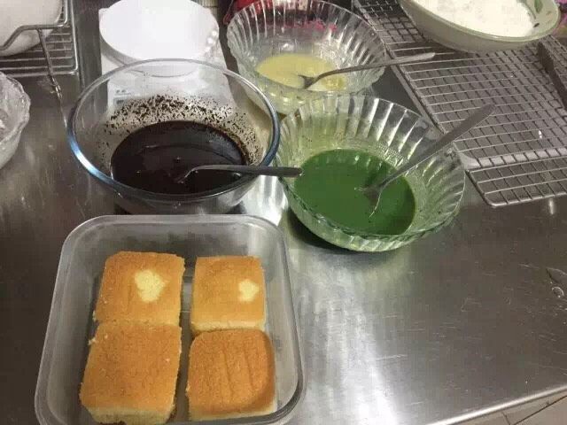 拉明顿蛋糕,黑巧克力放一个碗中,60g白巧克力和抹茶粉放一个碗中,60g白巧克力放碗中,一共三种颜色,分别隔水加热。倒入糖水调节浓度(砂糖水要一丢丢一丢丢的倒,慢慢调节浓度)。最后调好的浓度应该是比较粘稠的液体,有流动性用勺子翻起来低落是连续的,但是可以hold住纹路,酱汁滴在蛋糕上不会渗进去,只会附着在表面