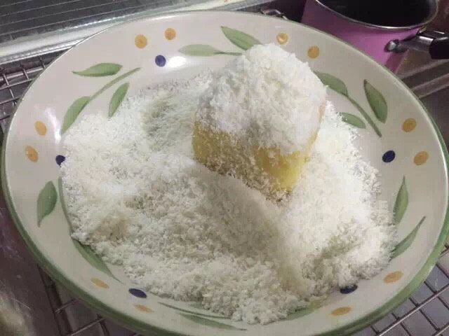 拉明顿蛋糕,四周沾满椰蓉,把多余的椰蓉拍掉