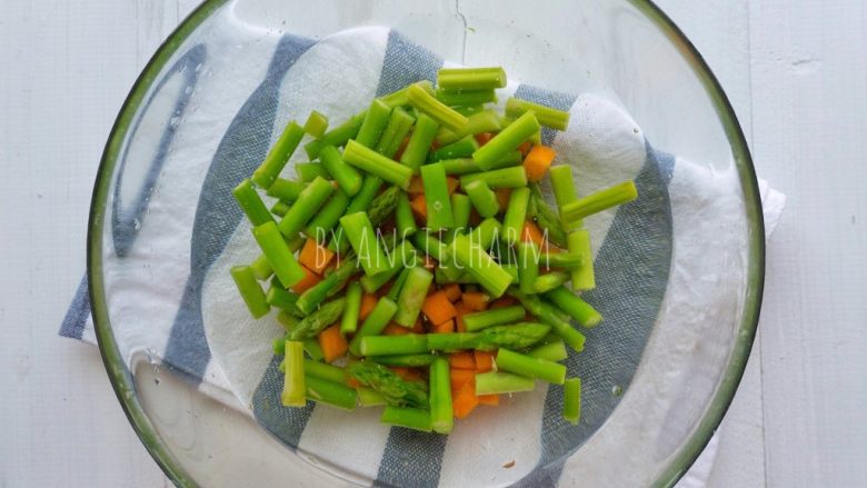 金枪鱼芦笋蛋炒饭,水煮沸后放胡萝卜丁,半分钟后,倒入芦笋再煮半分钟,捞出放入凉开水里浸泡。