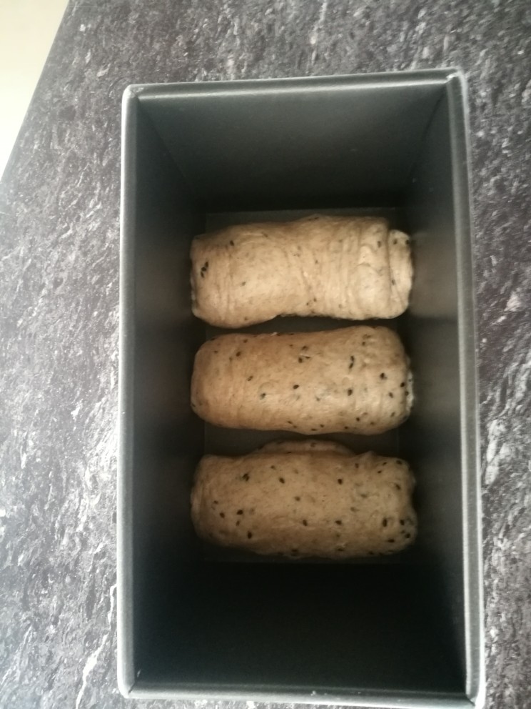 黑芝麻黑麦黄油吐司,放入吐司盒进行再一次发酵,在室温下发酵约一个半小时。
