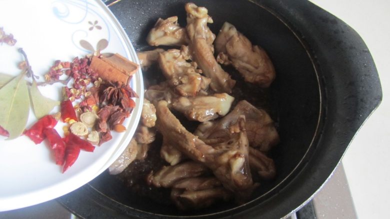 红烧鸭锁骨,翻炒至鸭锁骨表面微微发焦是加入准备好的姜片与大料进去翻炒;