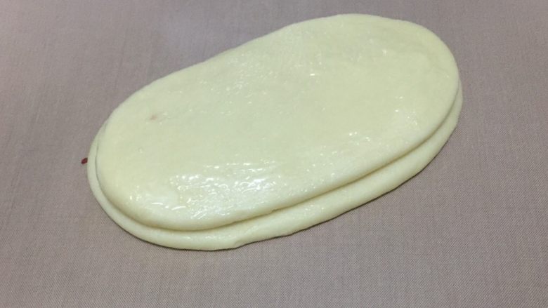 蔓越莓椰蓉千层吐司,再叠加一个擀好的长舌状面团,刷一层炼乳。大小尽量一致