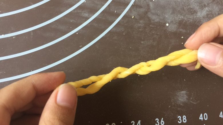 简单易做的小麻花,搓上劲后,将一端与另一端重合。此时面条会自动卷起来。再捏起两端,再同上一步骤一样往相反方向搓起来。