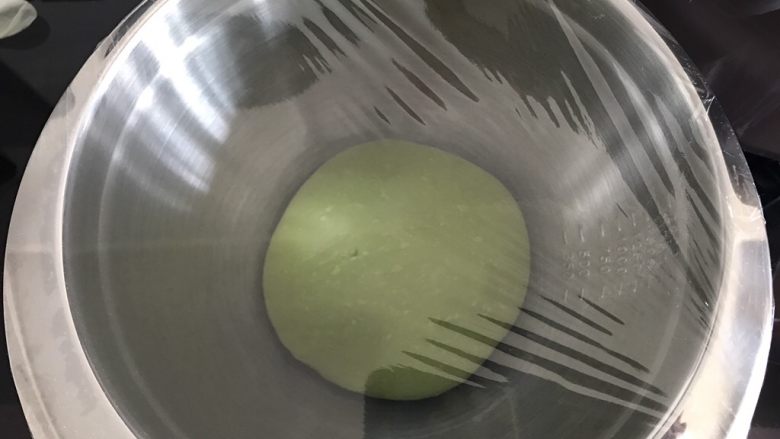 墨西哥抹茶蜜豆面包,将面团取出,团成圆团,放进干净面盆中盖上保鲜膜进行一次发酵。30度室温环境下发酵至原来两倍大。