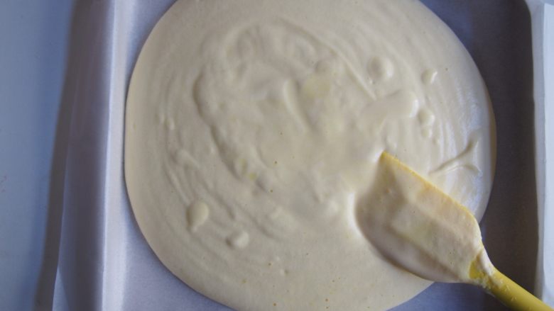 松软小四卷,烤盘上铺上油纸,将面糊倒入烤盘中