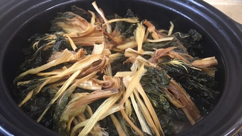 沙姜梅菜腩肉煲(简单版),放入锅中,再倒入一碗水。腌过菜干。大火煮开,中小火炖。中间你可以试试味,不够再加点味道。提醒一下,汁越收越入味。有的菜干是咸的,所以,看个人口味定咸淡啦。