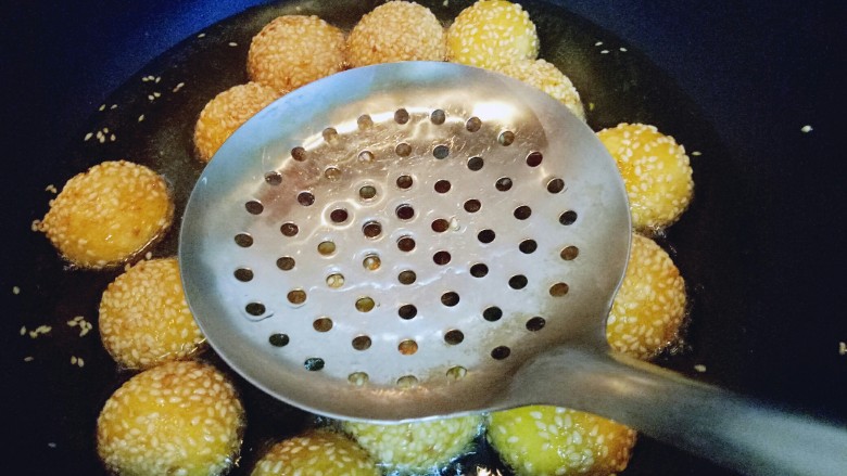 南瓜麻球,炸至麻球全部飘起来,用漏勺轻轻按麻球,反复多次按压,麻球明显的变大,继续小火炸至两面金黄即可捞出。