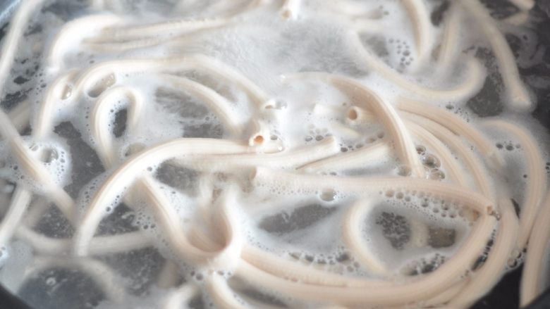 奥尔良空心炒面,锅里水烧开后，放入面条煮至五成熟，捞出过凉水备用。