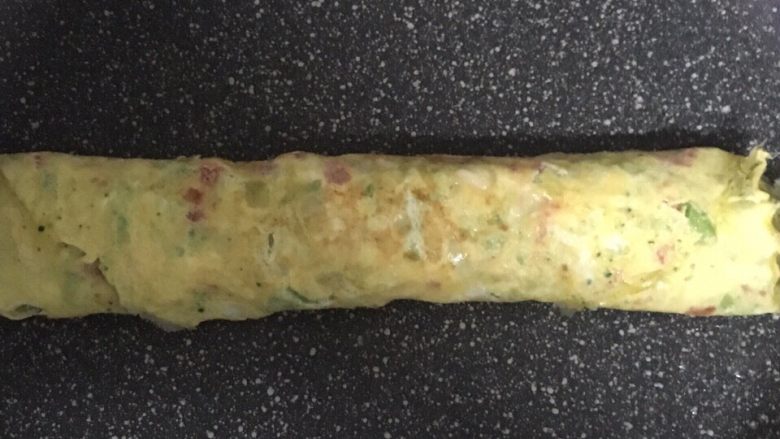 宝宝辅食之番茄芝士厚蛋烧,蛋液表面凝固后再次卷起,最后不断翻面煎至熟透。