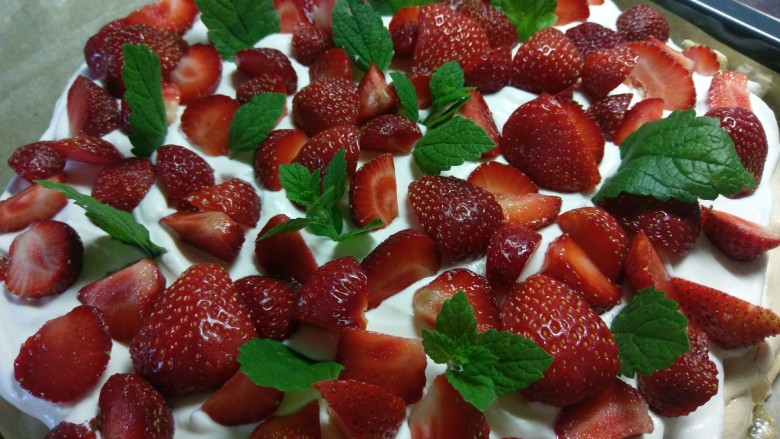 Pavlova 蛋白霜蛋糕,铺上草莓,再放点薄荷叶点缀