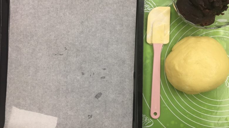豆沙蛋黄馅麻薯饼,准备油纸铺在烤盘上,烤箱预热180度10分钟。