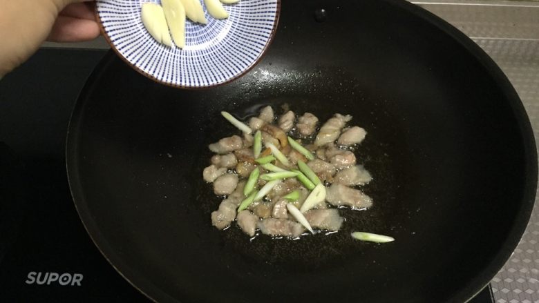 盐煎肉,倒入蒜片,炸香