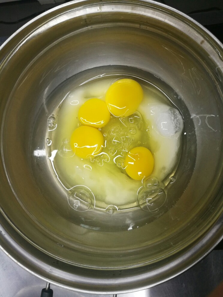 彩虹蛋糕胚制作方法,把盛有鸡蛋和糖的玻璃碗放在热水中,隔水加热,蛋液和糖拌匀,温度到40℃取出玻璃碗准备打发。