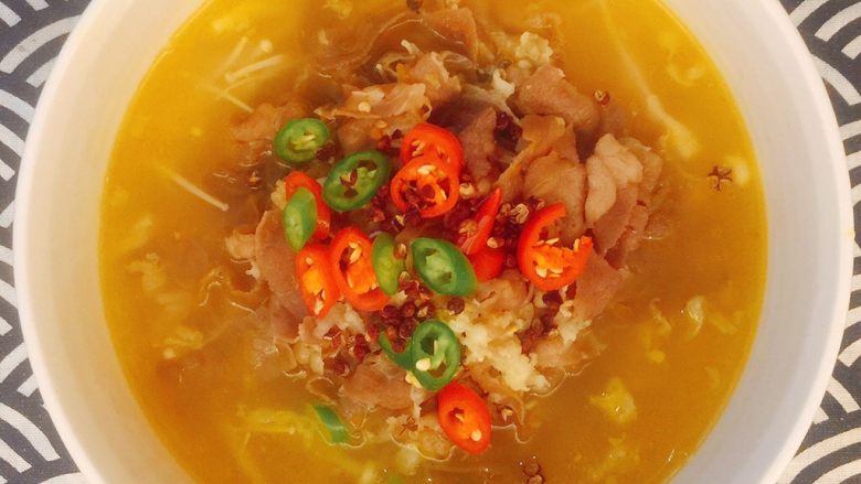 极品酸汤肥牛,把酸汤倒入碗里,撒上青红小米椒圈点缀,放几粒花椒;