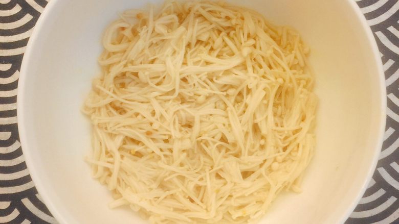 极品酸汤肥牛,煮好的金针菇捞出,平铺到碗底;