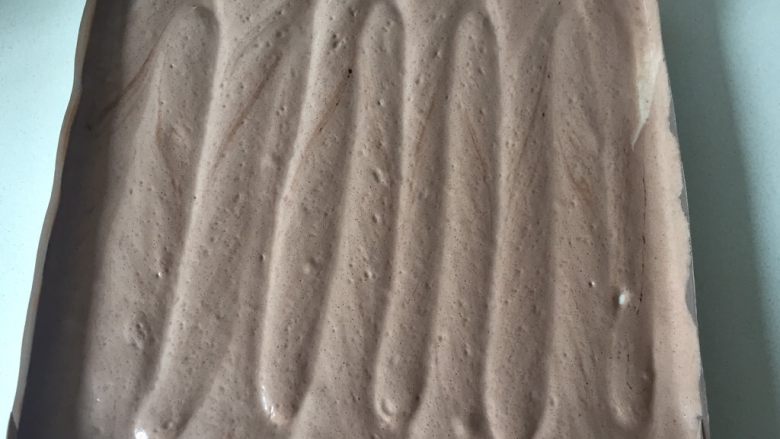 可可旋风瑞士卷(后蛋法),将烤盘旋转90度,垂直于刚才的纹路同样的手法再划一遍。
这里要记住第二次你划的方向,等会卷起来的时候一定要平行于第二次划的纹路来卷,否则就不会出现旋风纹路。