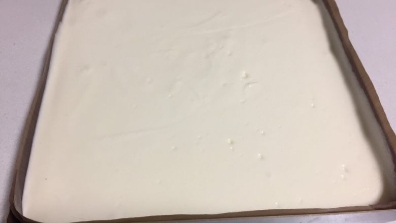 可可旋风瑞士卷(后蛋法),金盘里铺上油纸或油布,把三分之二的蛋白霜缓缓倒进金盘,抹平表面放置一边。