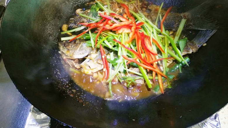 豆瓣鲫鱼,大约二分钟后放入青红椒丝和芹菜,大火收汁加入鸡精。