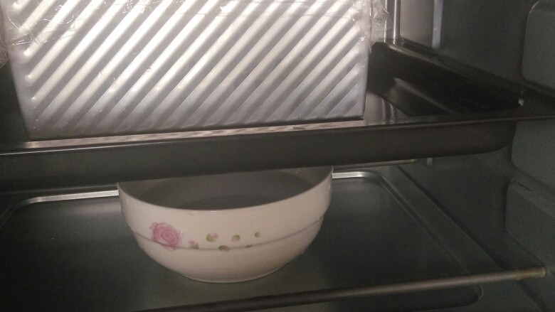金砖土司,烤箱底部放一碗热开水,土司模具连同烤盘一起放入烤箱,进行二次发酵。