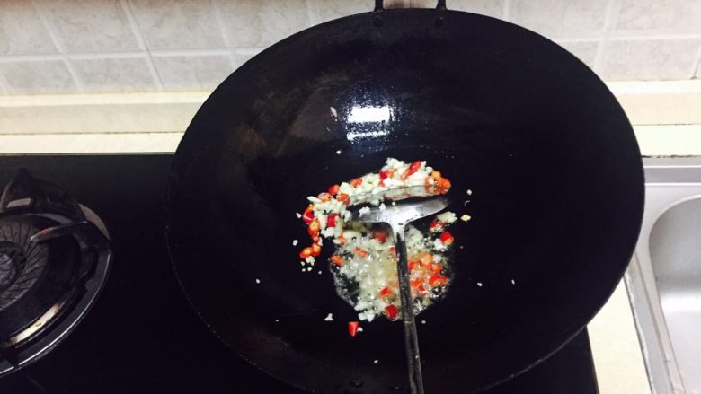 神下饭之酸苦瓜炒卤肥肠,再加少许油加热,倒入小米椒碎和蒜末炒香。