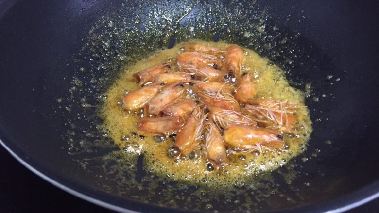 鲜虾豆腐煲,接着来处理虾头,锅中倒入适量油,烧热下虾头,虾出虾油,炸至虾头金黄,如图,关火,夹出虾头,留虾油在锅中