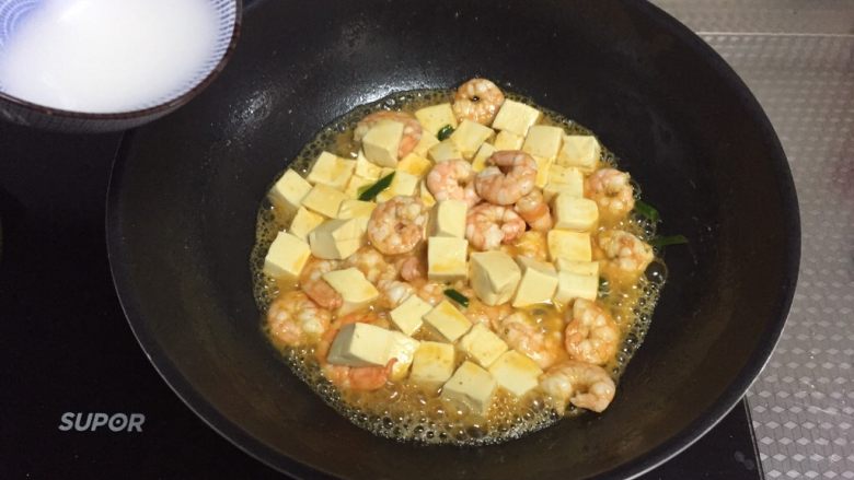 鲜虾豆腐煲,倒入调好的水淀粉,翻炒均匀至汤汁浓稠,撒盐,炒匀即可